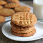 Stack of peanut butter cookies in white plate.