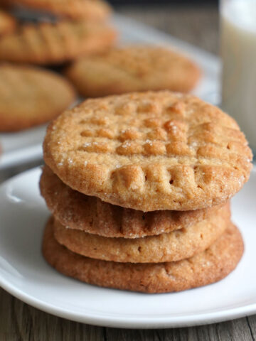 Stack of peanut butter cookies in white plate.