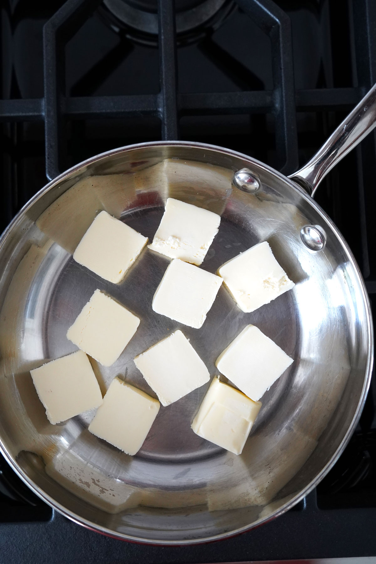 Butter slices spread across the bottom of a stainless steel pan.