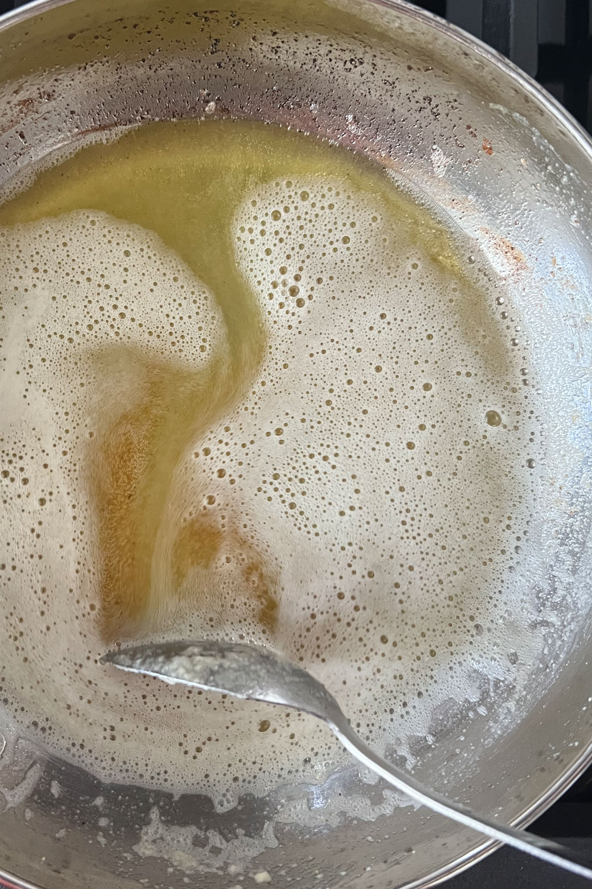 Melted butter foaming in a pan starting to become brown.