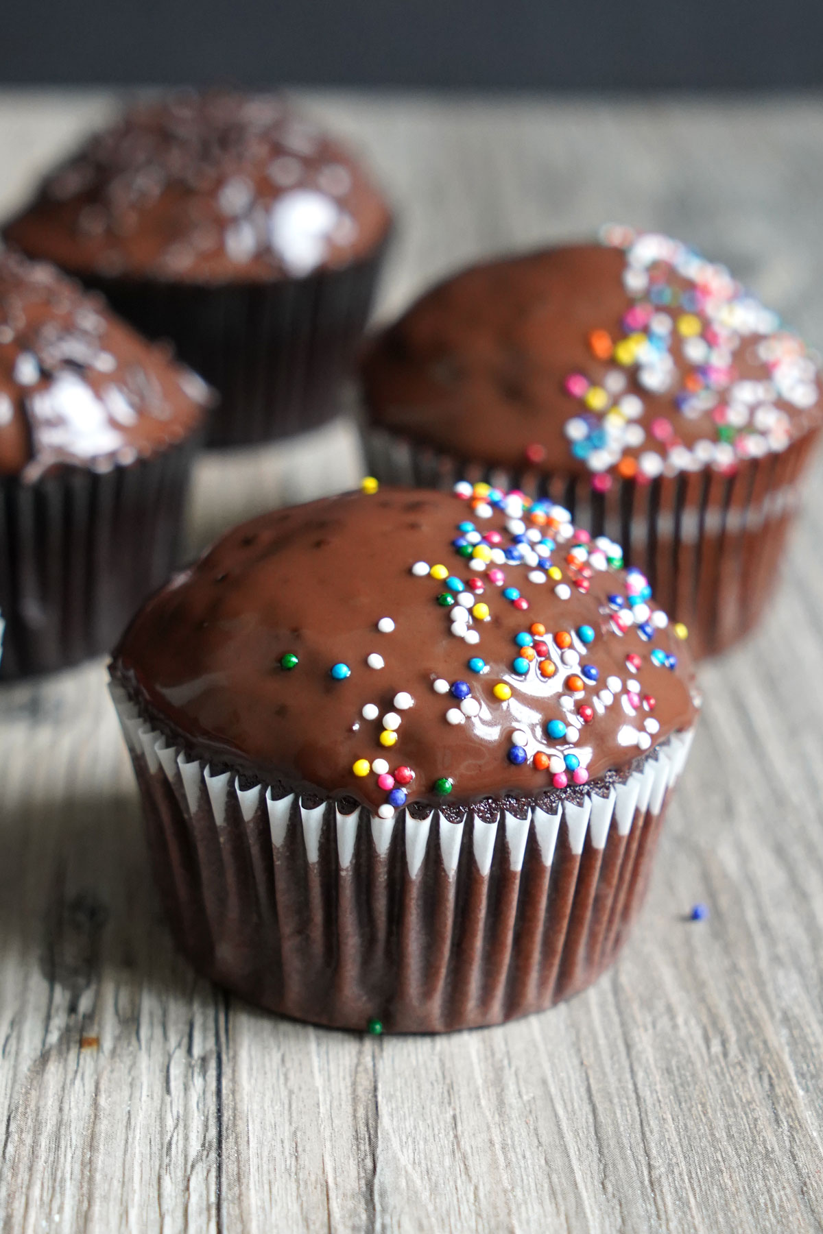 Dark chocolate cupcakes with rainbow sprinkles.