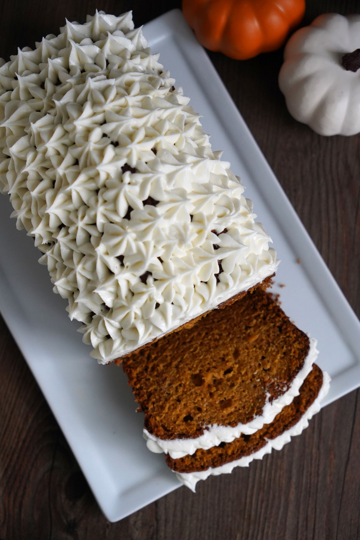Top view of frosted pumpkin bread with two slices.