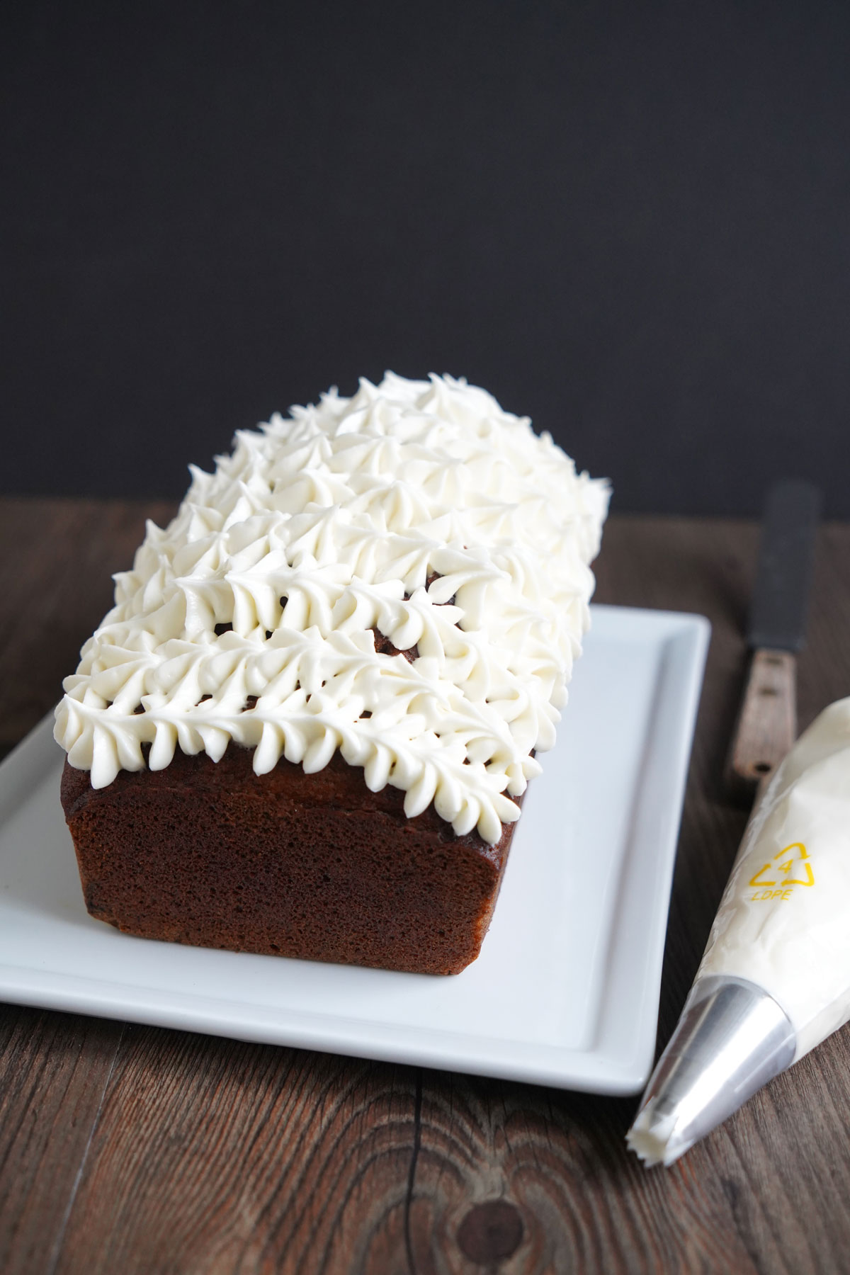 Pumpkin bread loaf with cream cheese frosting piped with star tip.