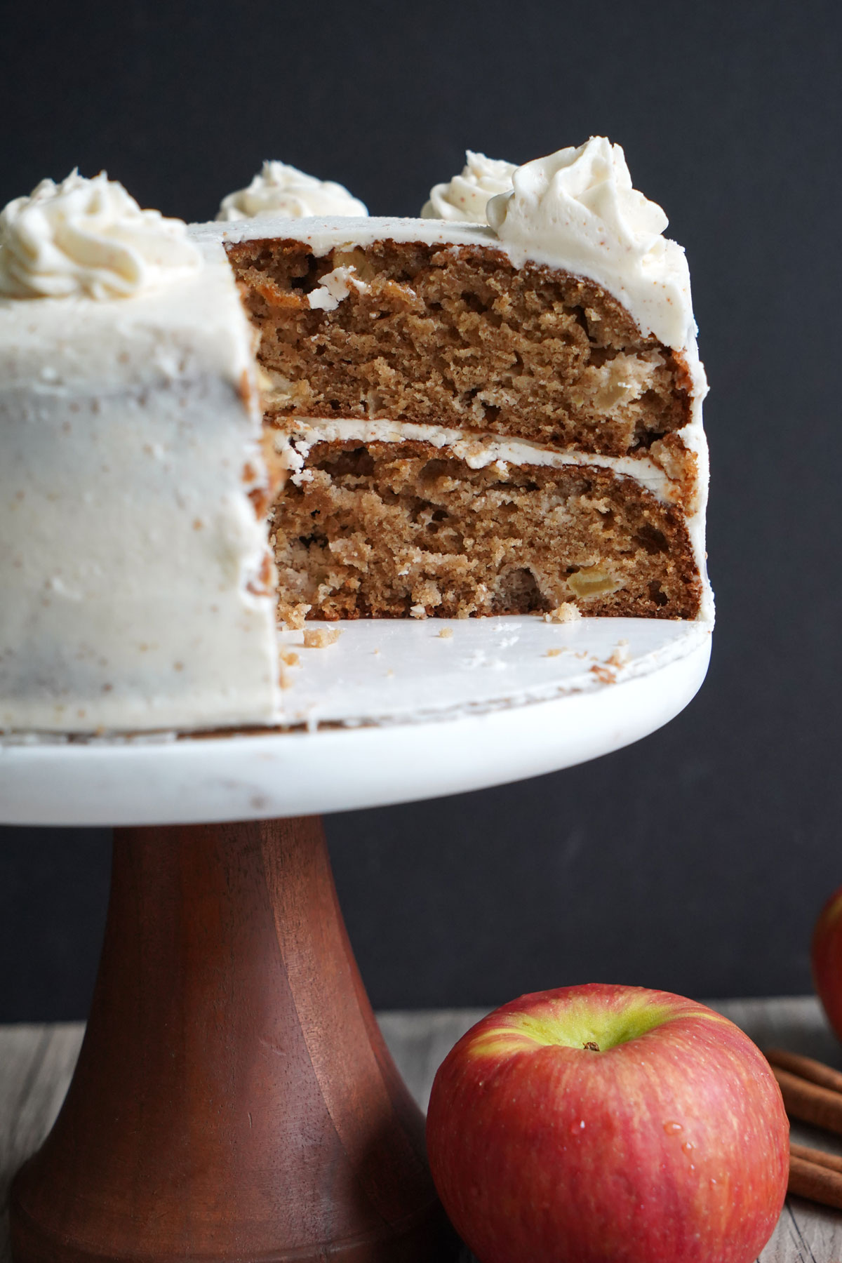 Apple spice cake on a cake stand with slices cut out.