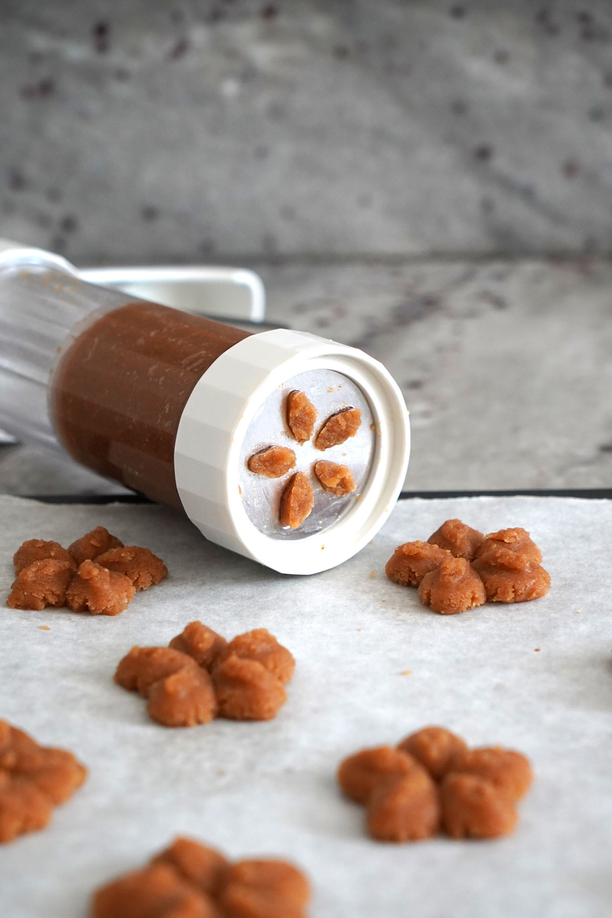 Cookie press being used to make flower shaped peanut butter blossoms.