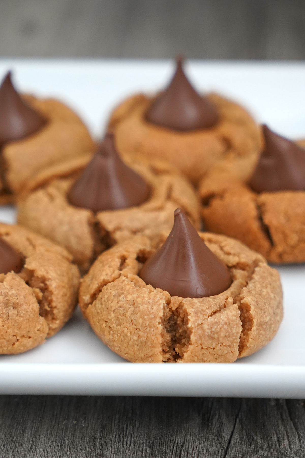Close up view of peanut butter blossom cookies on white plate.