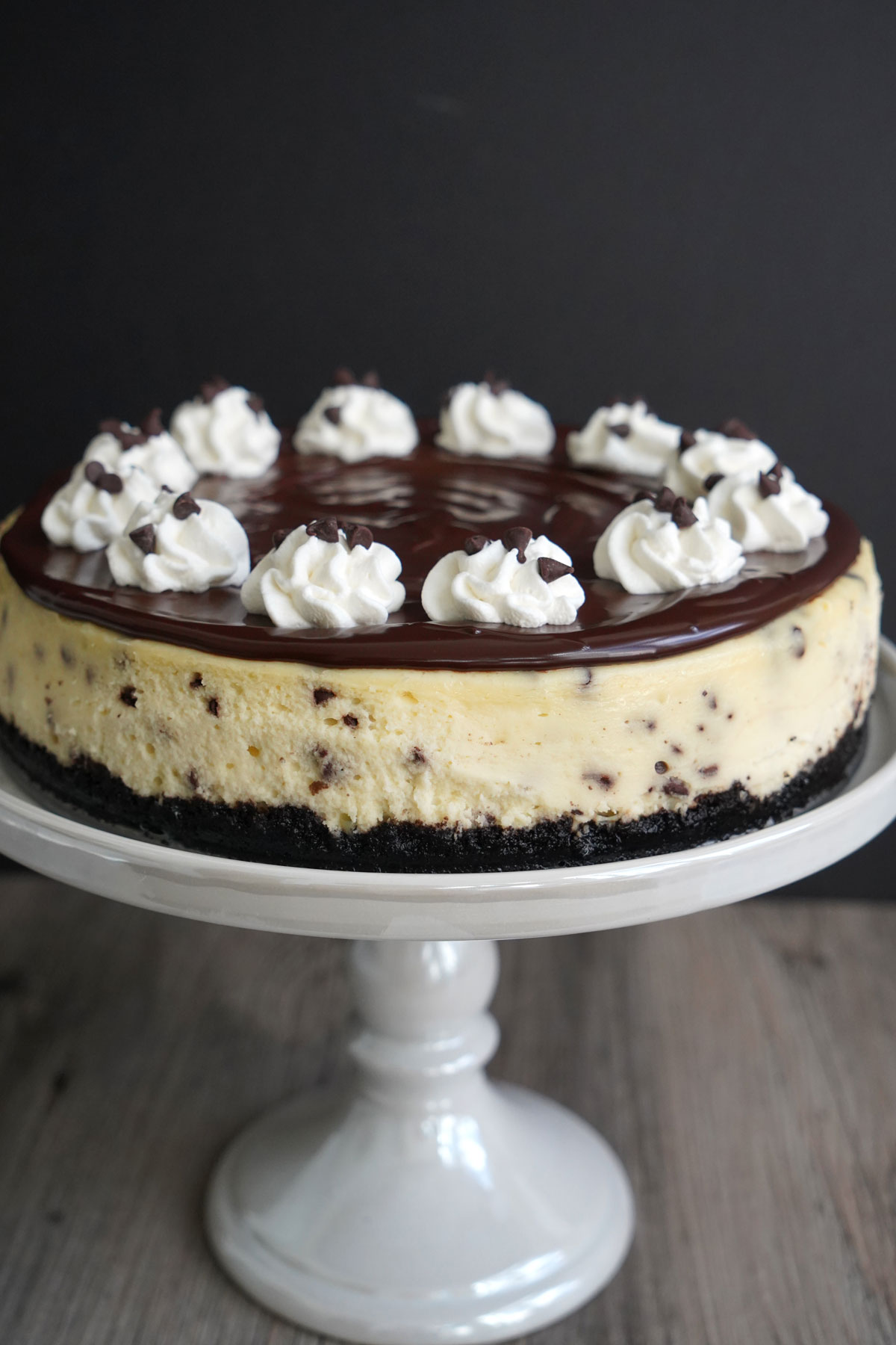 Chocolate chip cheesecake on a cake stand.