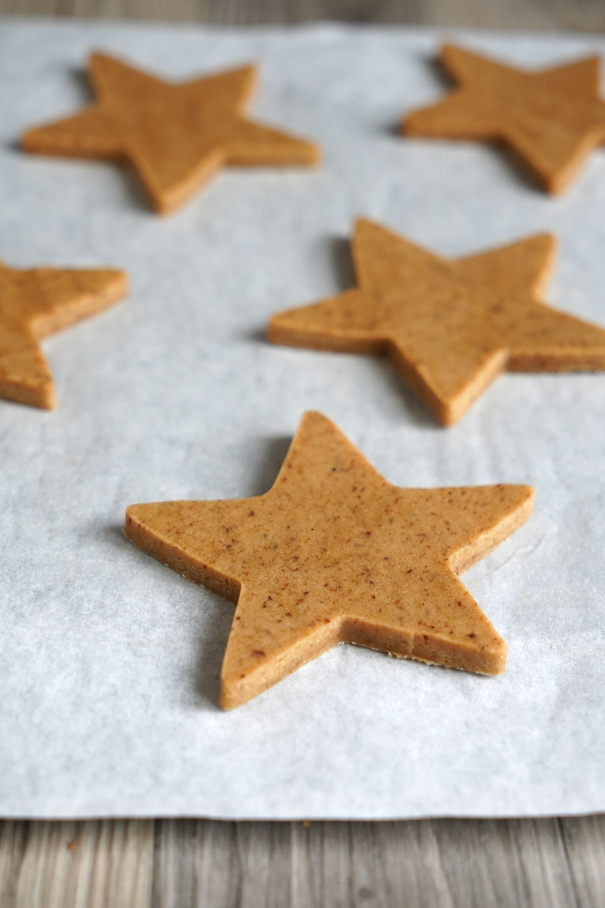 Star shaped espresso flavored cookies unbaked on a parchment sheet. 