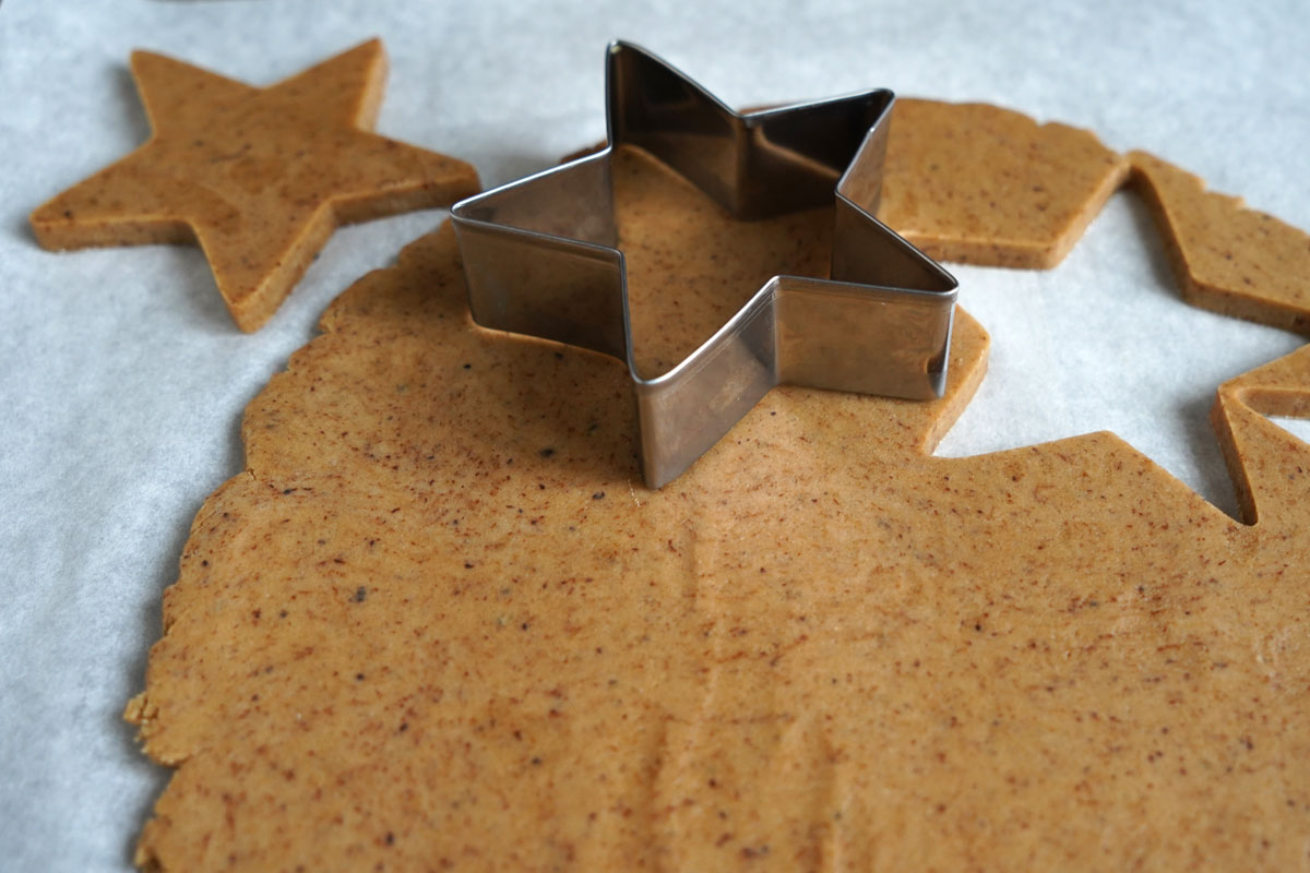 Star shaped cookies being cut from coffee flavored sugar cookie dough.