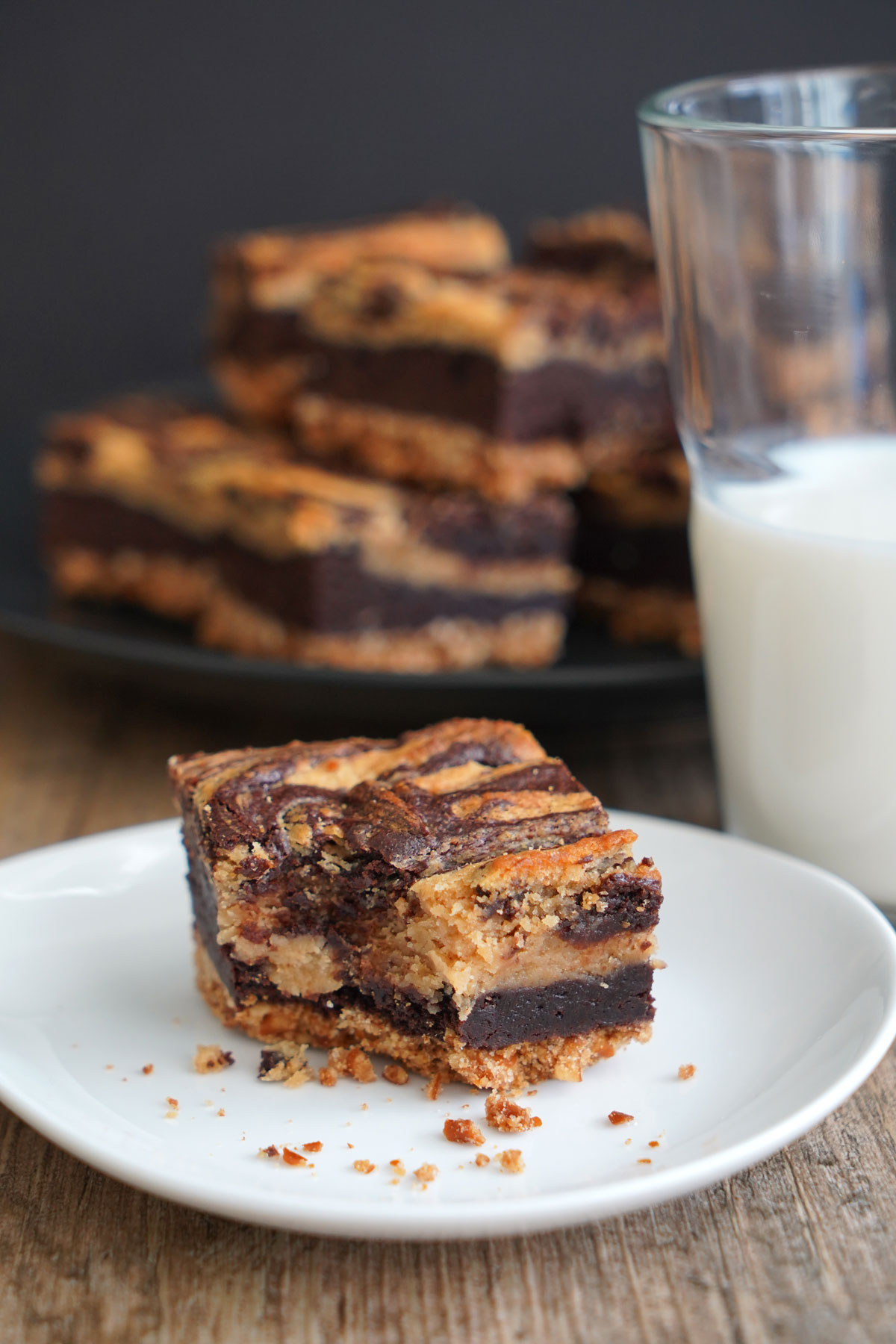 Peanut butter cheesecake brownie on white plate with bite taken. 