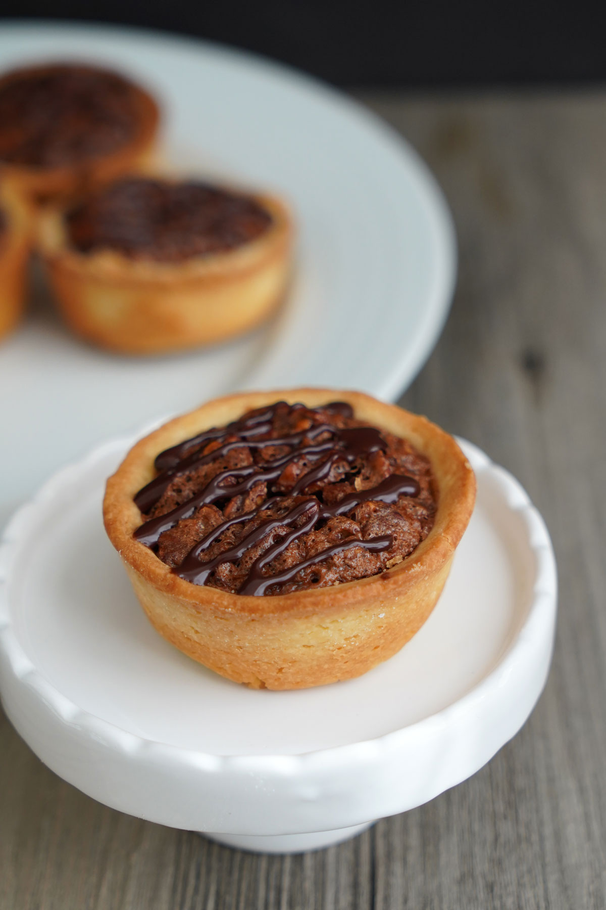 SIngle mini pecan pie on small white pedestal.