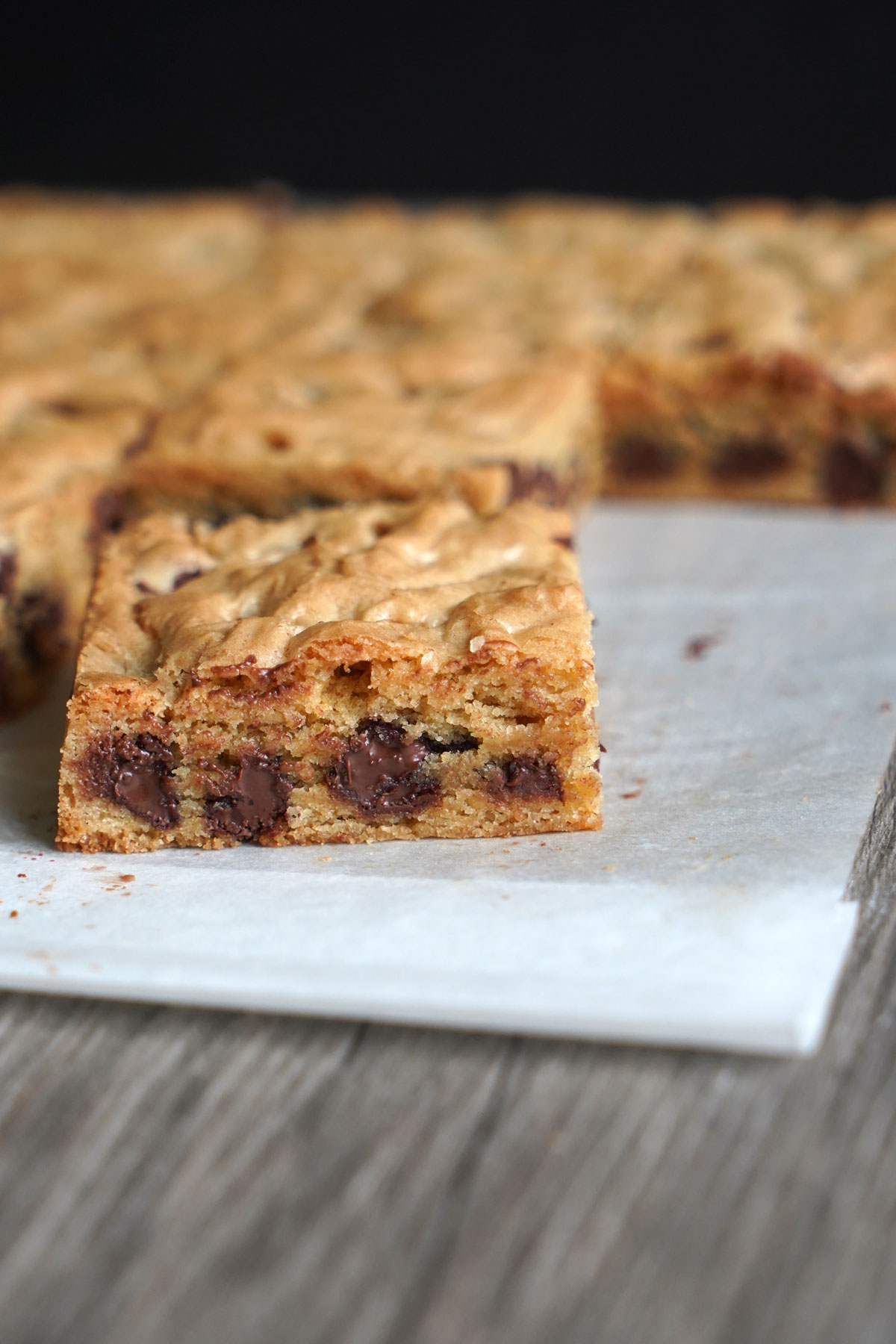Close up of chocolate chip cookie bar on parchment paper.