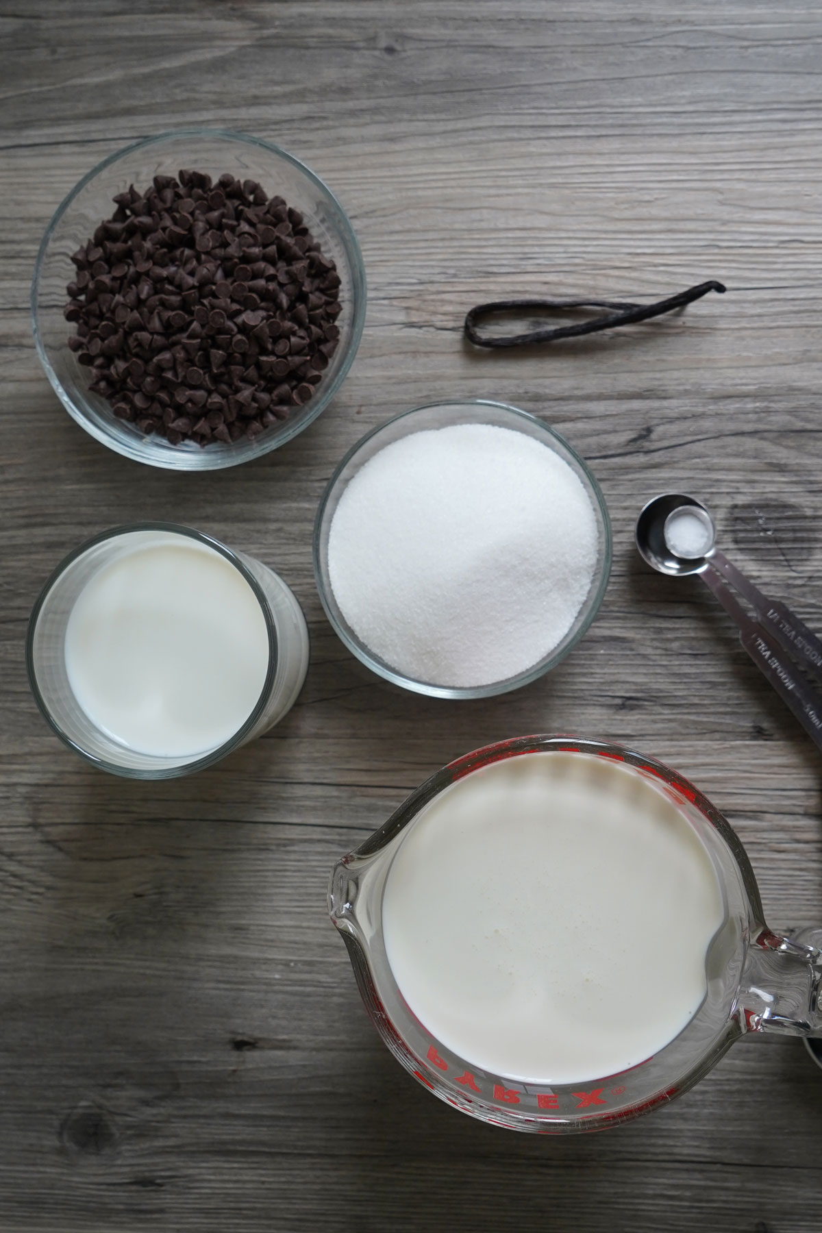 Ingredients for making ice cream: chocolate chips, suge, milk, cream, vanilla bean, salt.