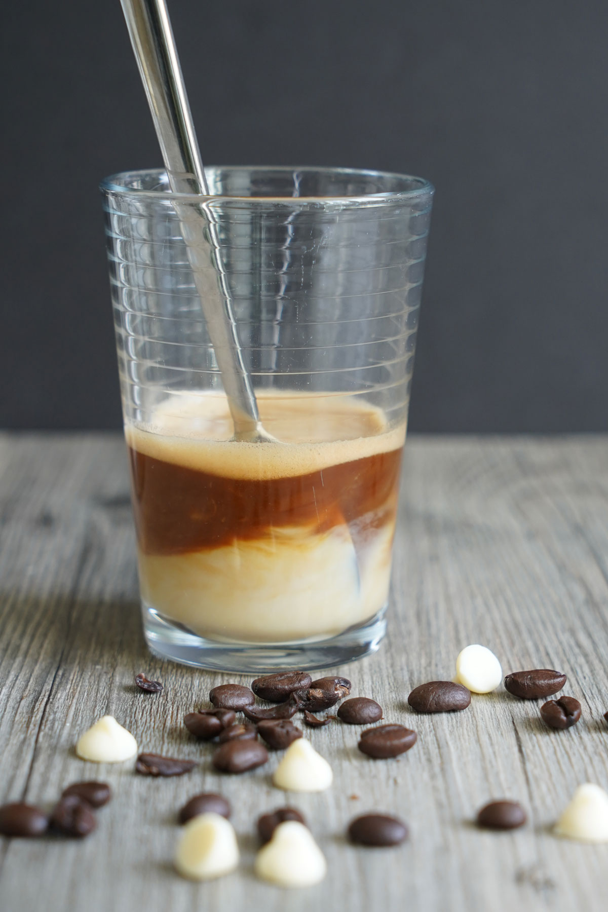 White chocolate sauce being stirred into a shot of espresso.