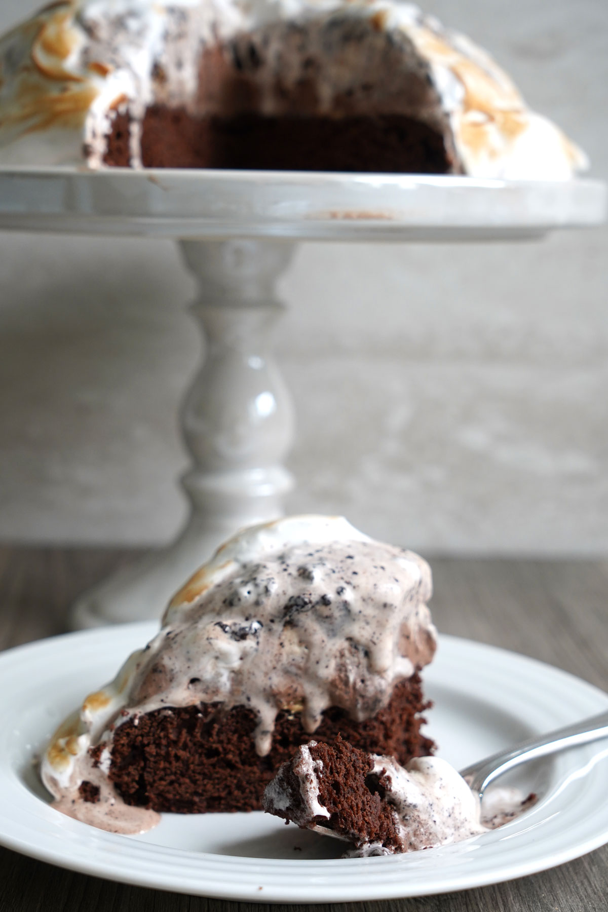 Slice of baked Alaska on white plate with fork.