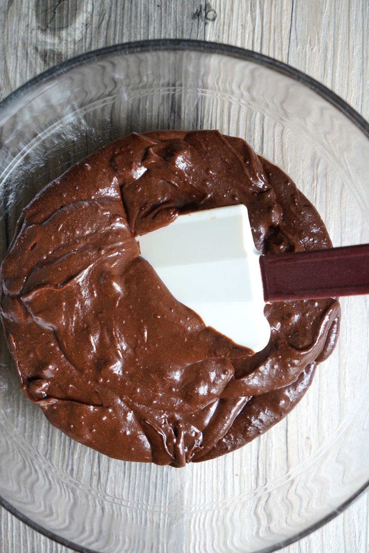 Mixing bowl filled with glossy chocolate brownie batter ready to be poured into a baking pan