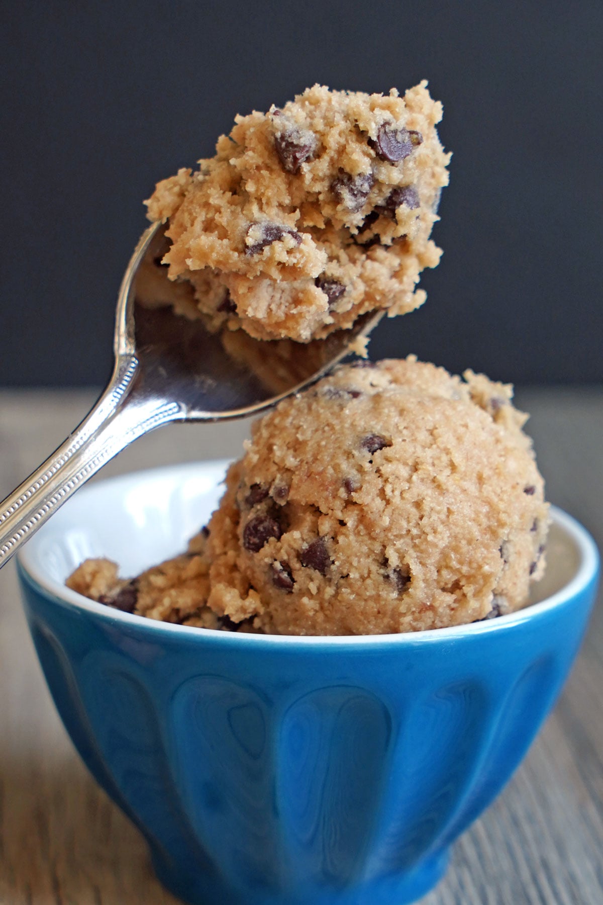Close-up of a spoon holding edible cookie dough with mini chocolate chips.


