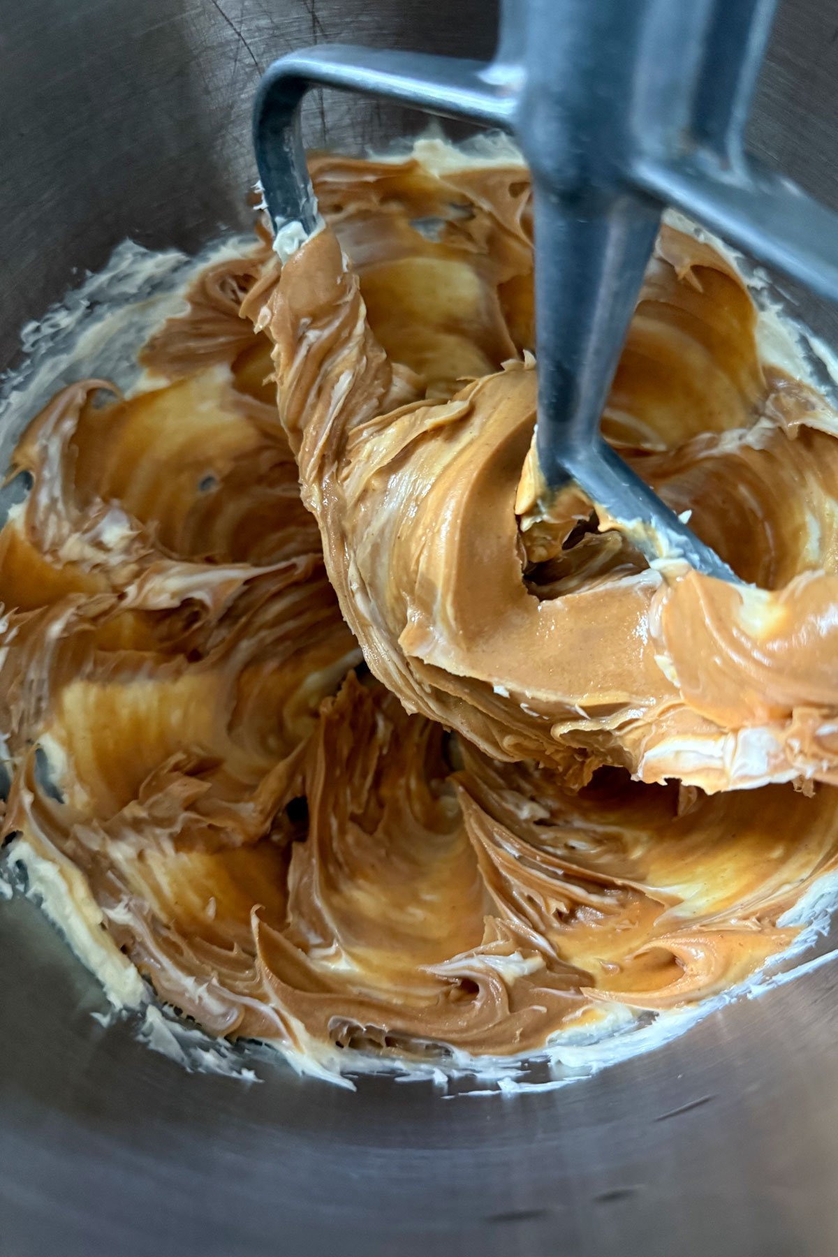 Peanut butter and unsalted butter being mixed in stand mixer.