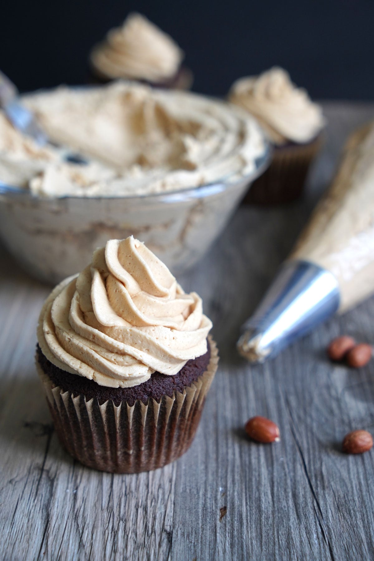 Chocolate cupcake with peanut butter frosting. Frosting bowl and piping bag in background.