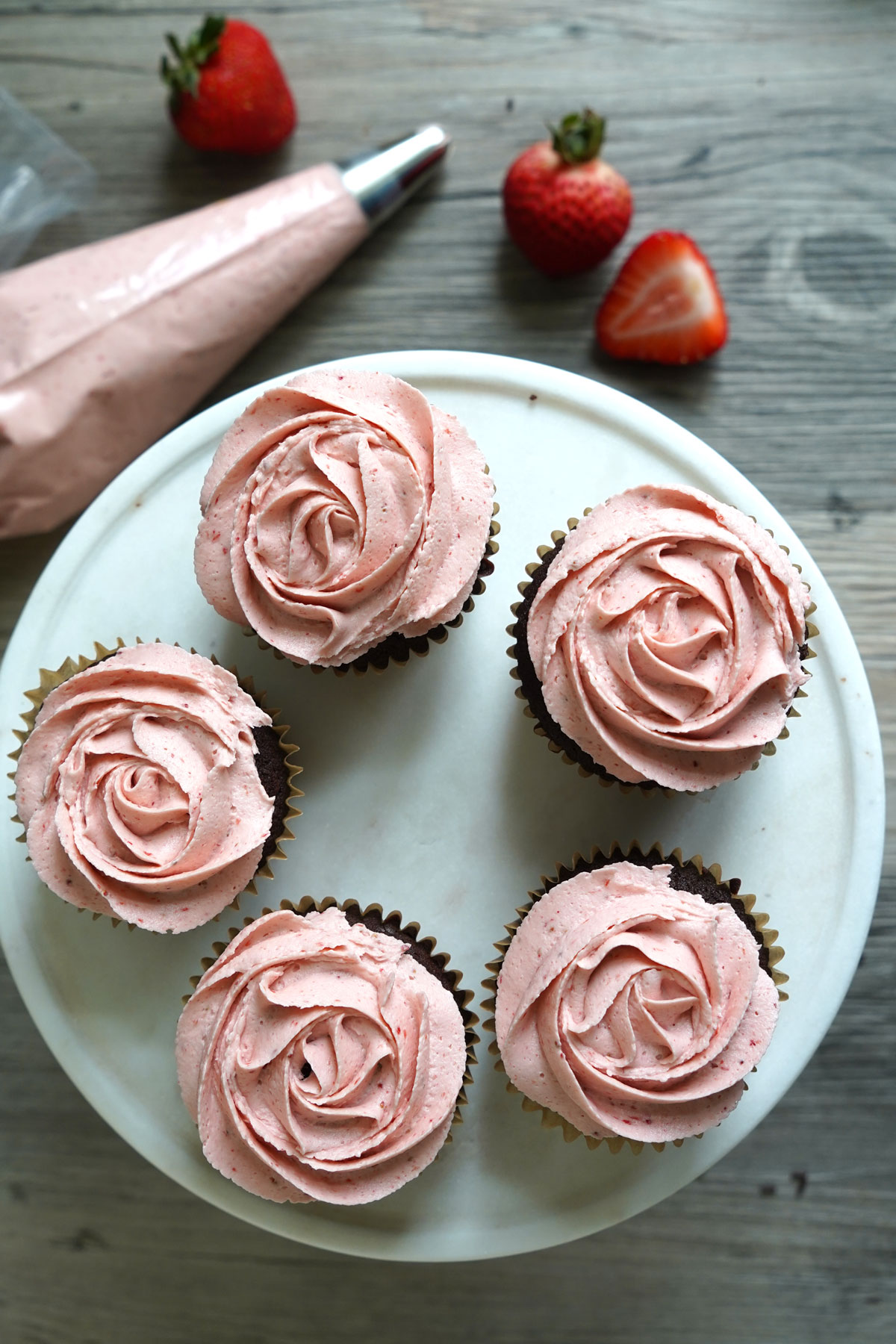 Top view of cake platter with chocolate cupcakes frosted with strawberry buttercream.