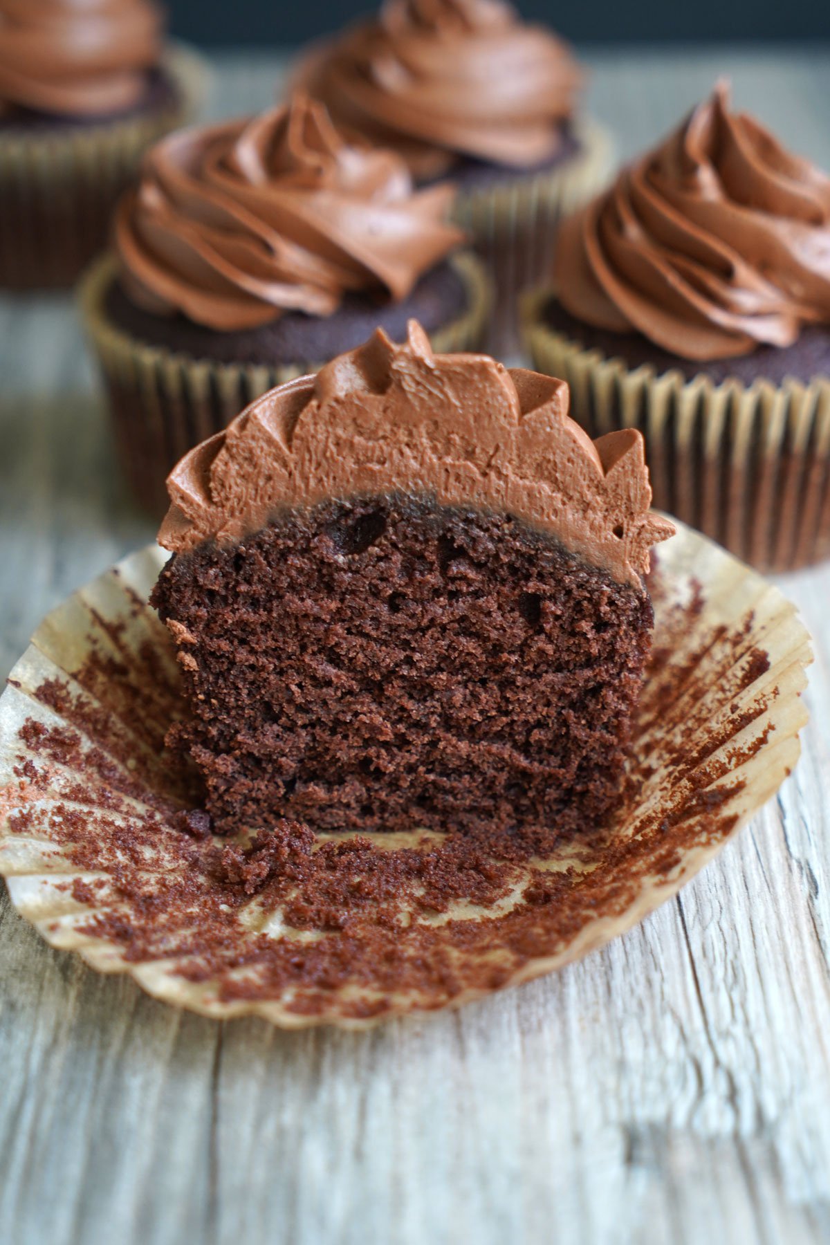 Chocolate cupcake frosted with chocolate fudge frosting. Cut in half to show crumb texture.