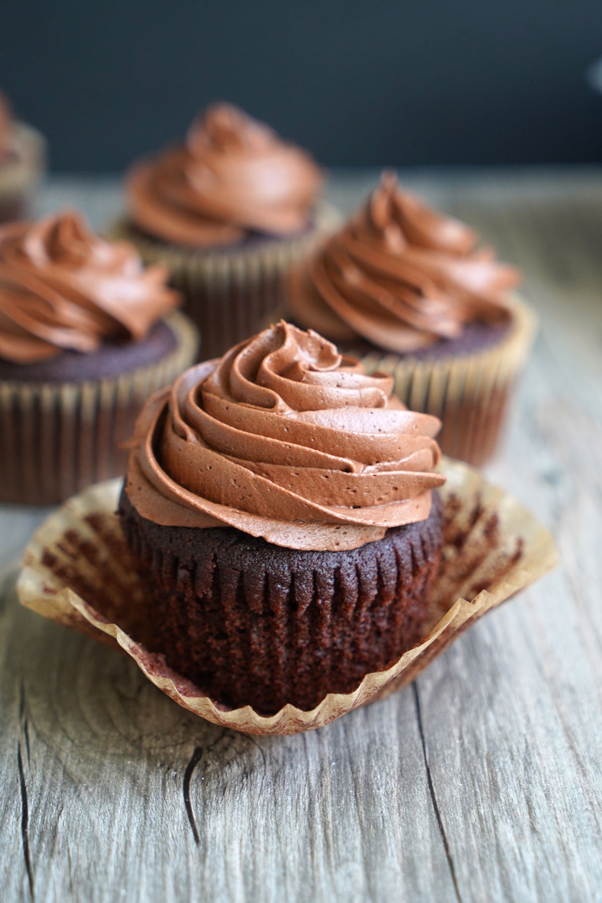 Chocolate cupcake frosted with chocolate fudge frosting. Wrapper opened to show cake.