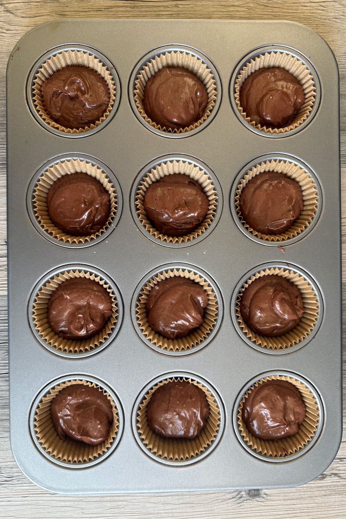 12 cup cupcake pan filled with chocolate cupcake batter. 