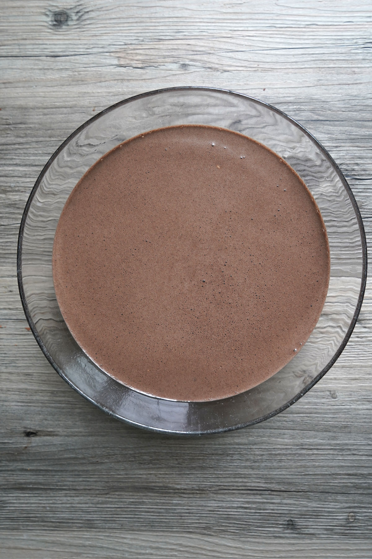 Chocolate crepe batter in a glass bowl resting.