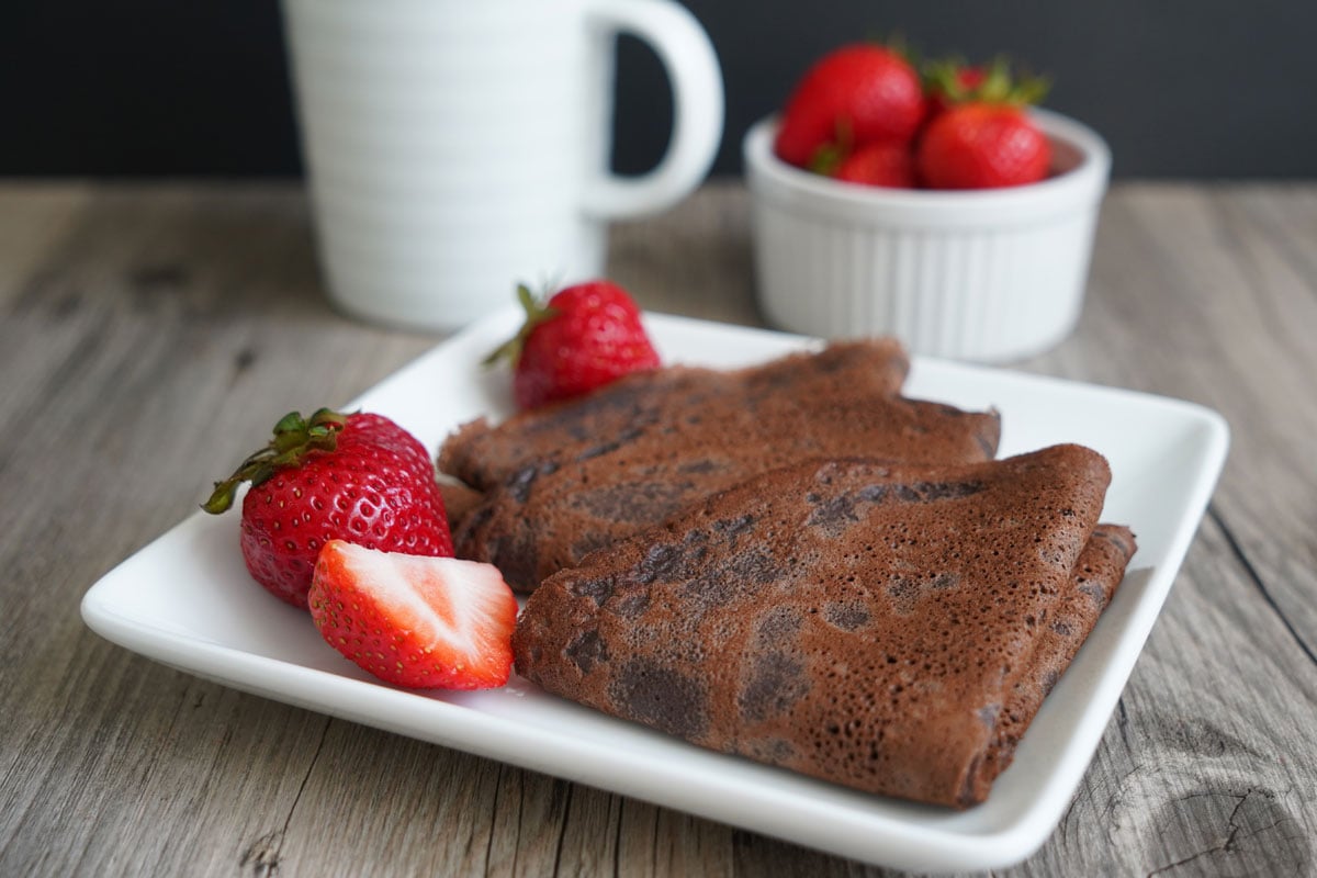 Chocolate crepes in a plate with strawberries.