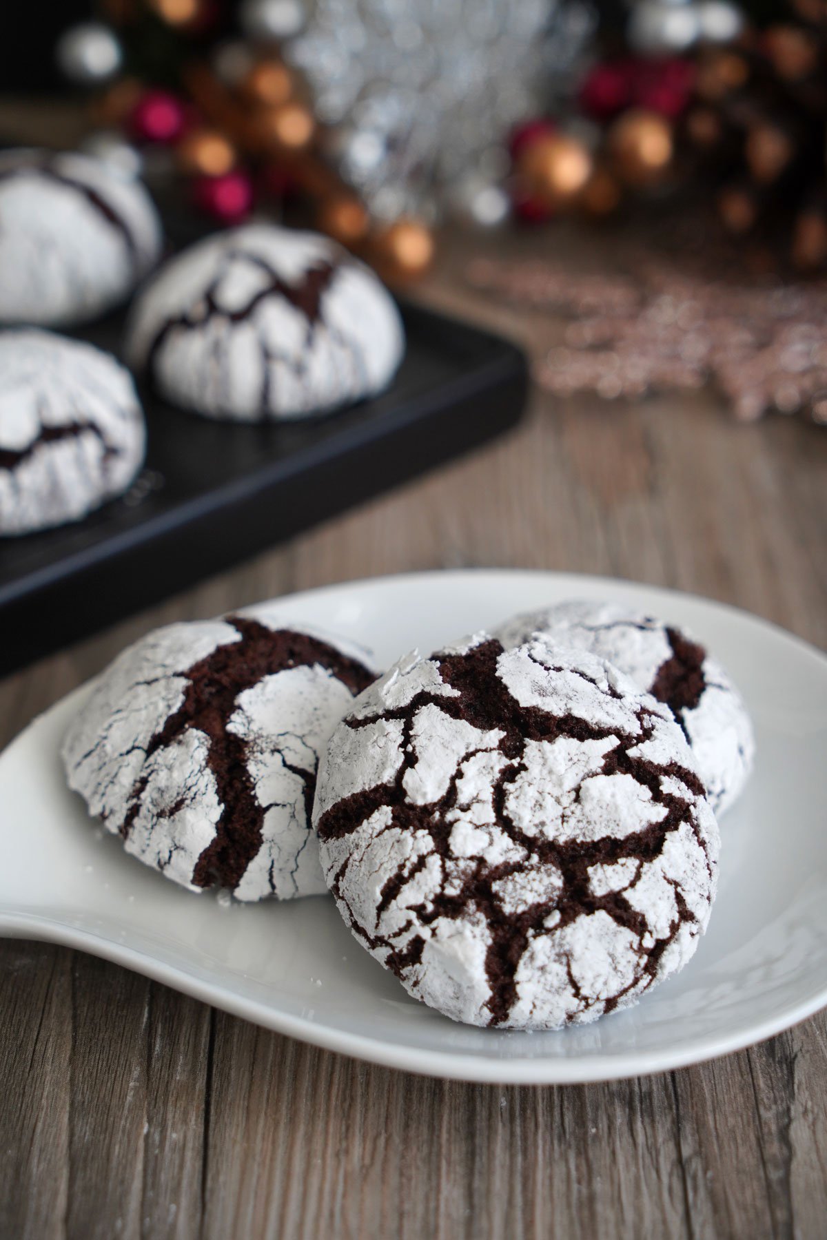 Close up photo of chocolate crinkle cookie on a plate to show the powdery crackles.