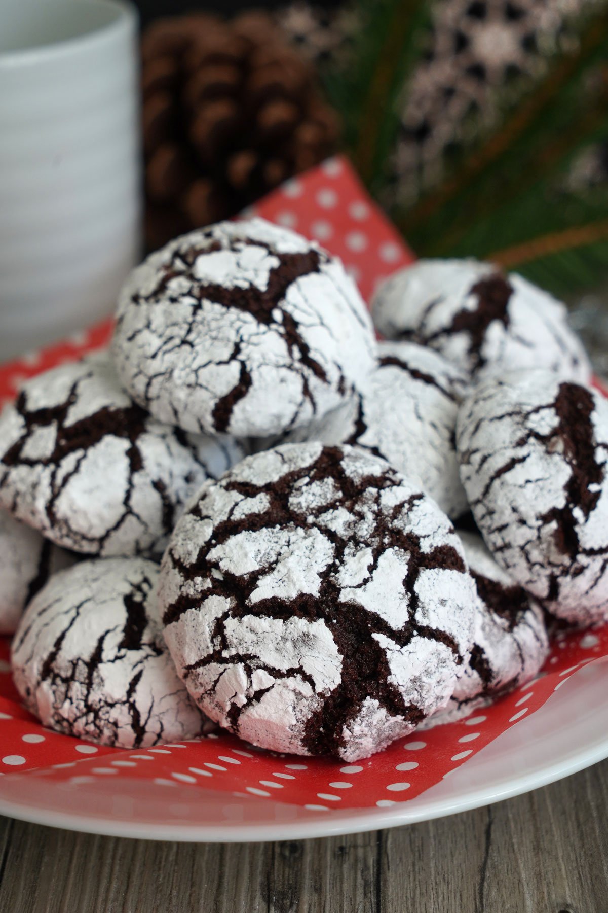 Chocolate crinkle cookies piled on plate lined with decorative red parchment. Ready for serving.