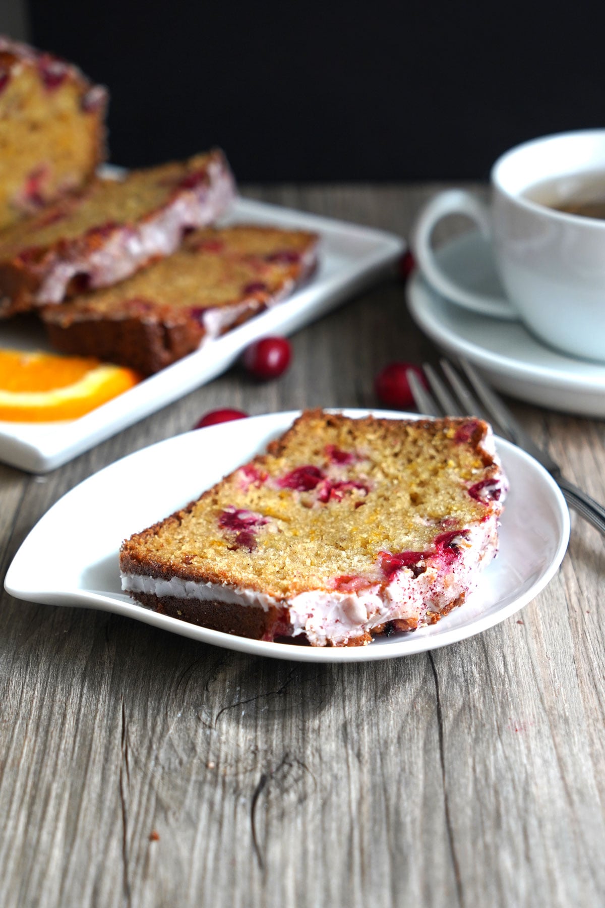 Alice of spiced orange cranberry bread on a plate served with tea.