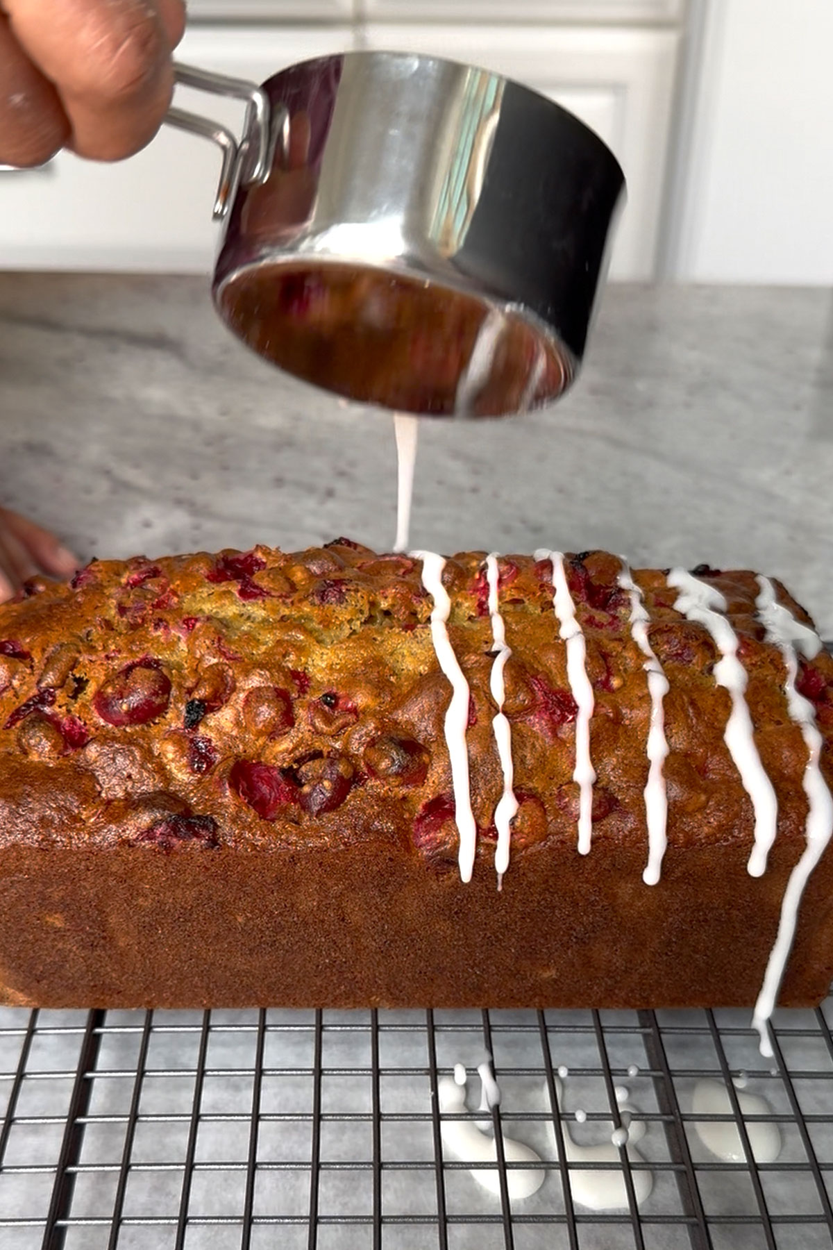 Icing being drizzled over finished cranberry bread.