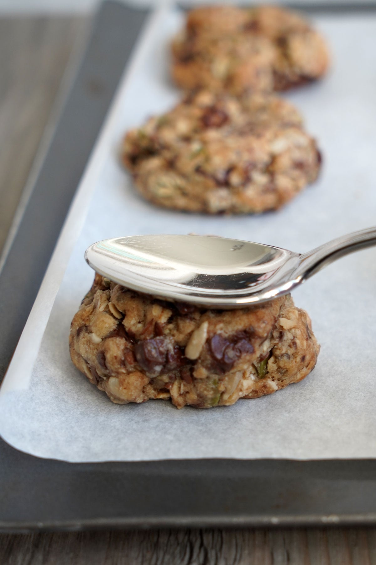 Spoon pressing down on center of baked cookie. 