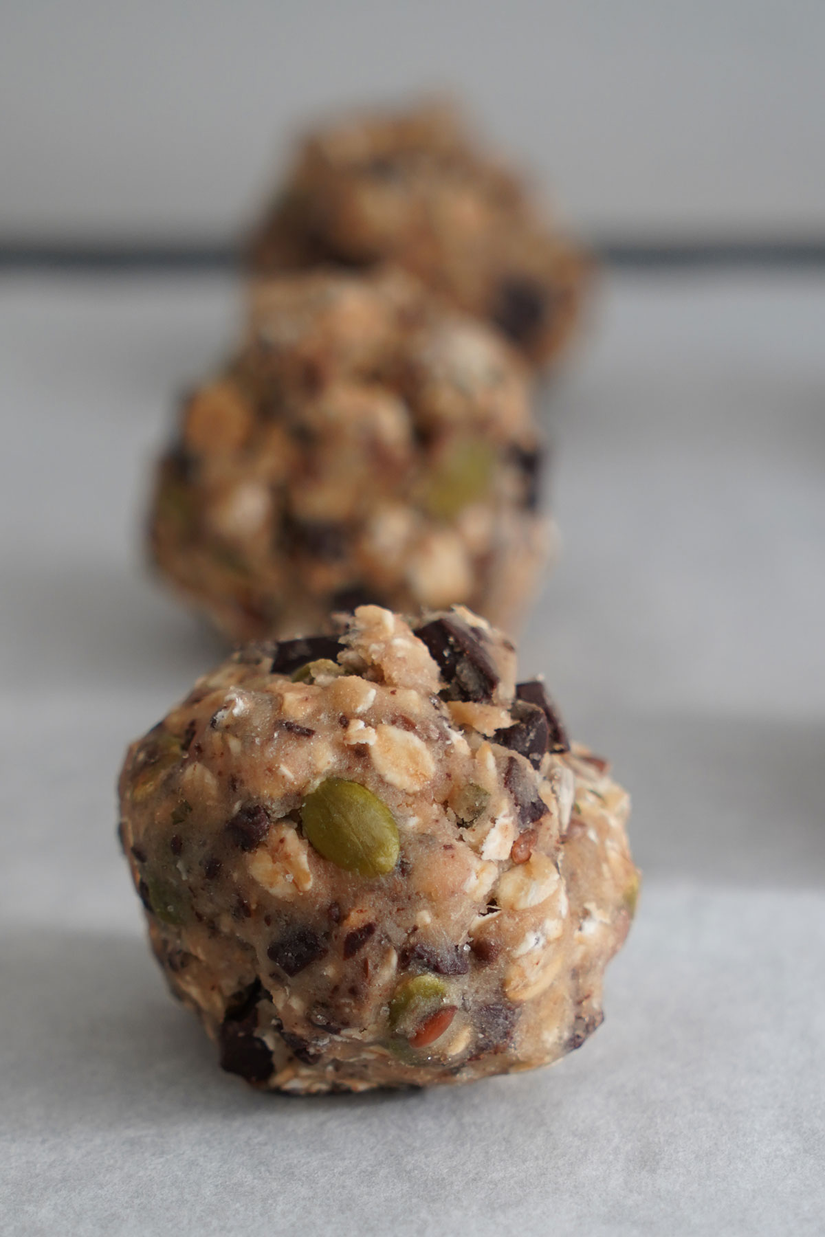 Close up of cookie dough ball showing the seeds, oats and chocolate. 