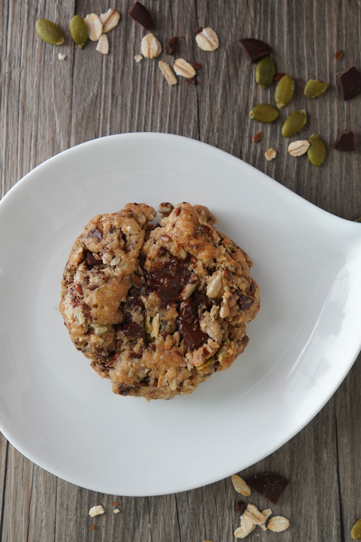Top view of baked oat and seed chocolate chunk cookie showing the melted chocolate puddles. 