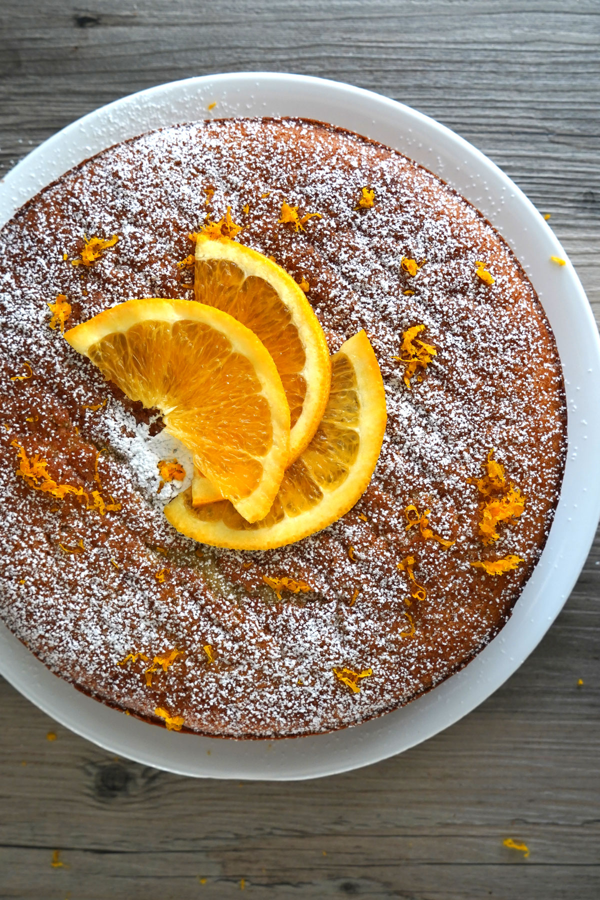Top view of garnished finished cake with confectioners sugar and orange slices.