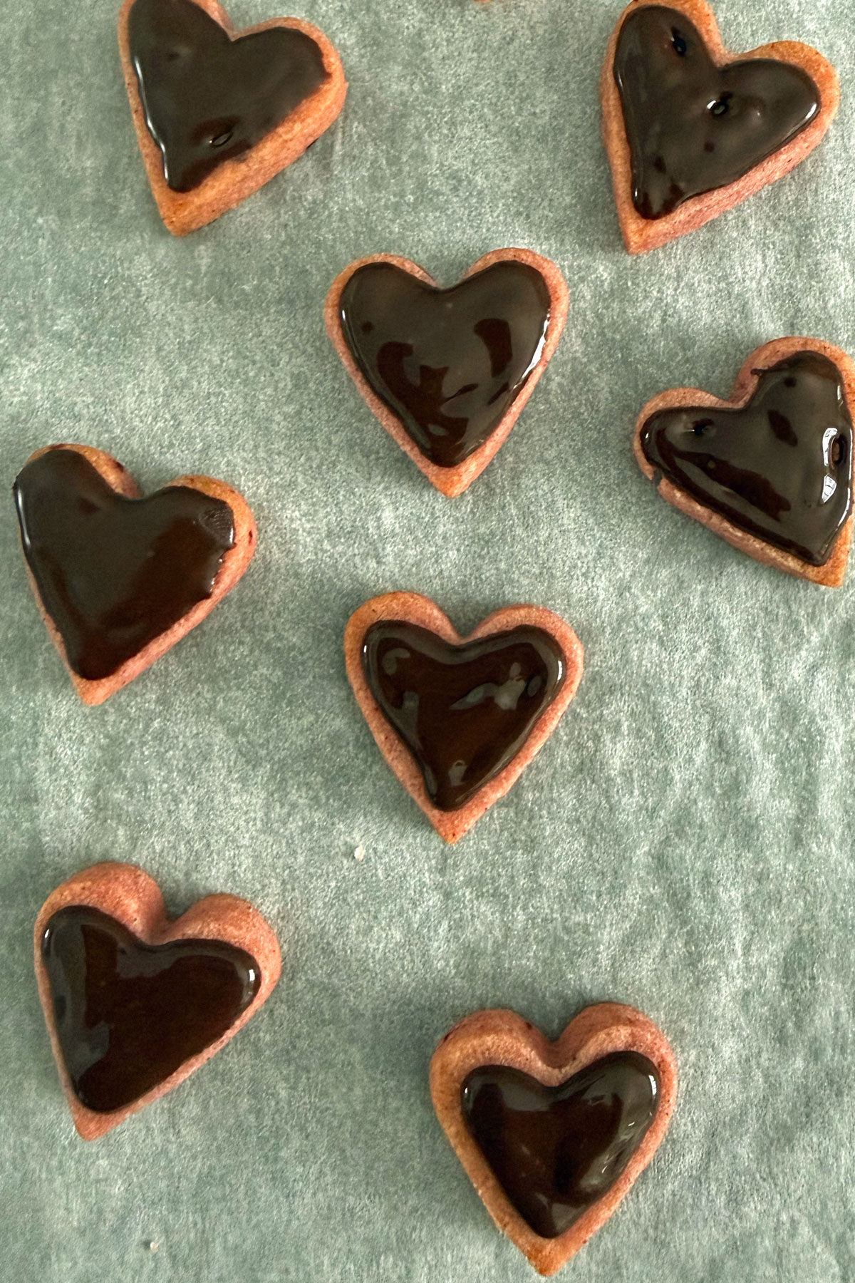 Mini pink heart shaped cookies coated with chocolate on top.
