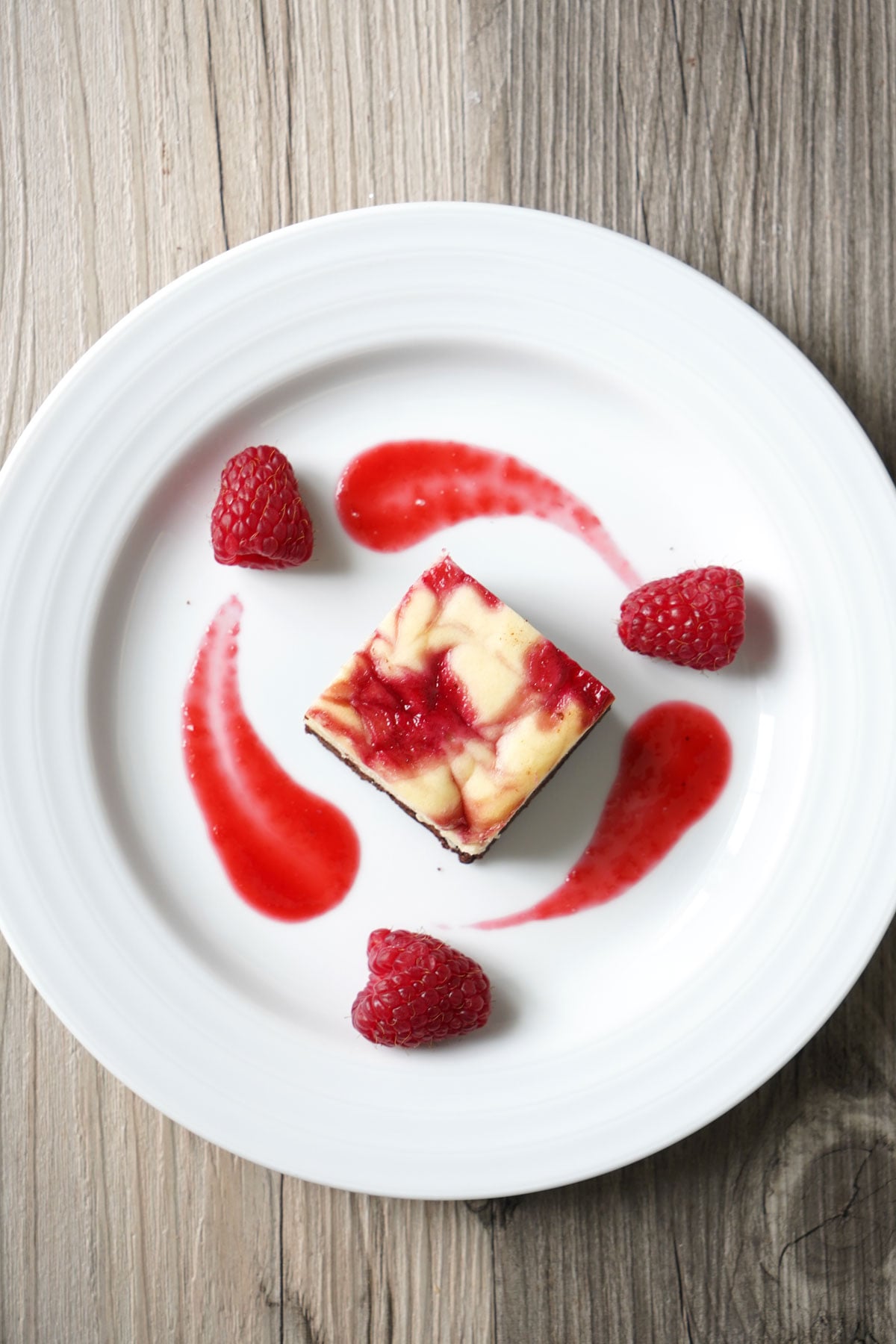 Raspberry cheesecake brownie plate with raspberry sauce.