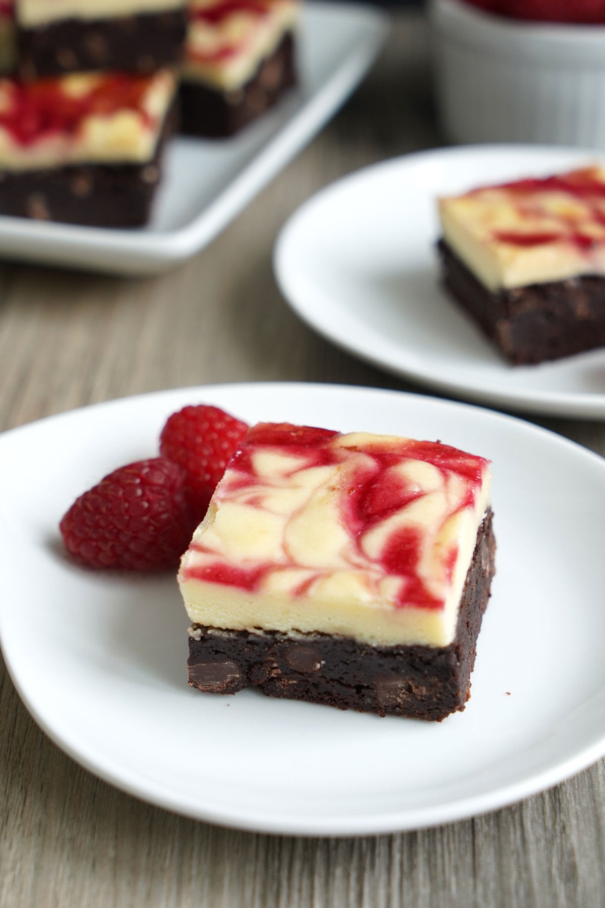 Single brownie served on a plate with raspberries.