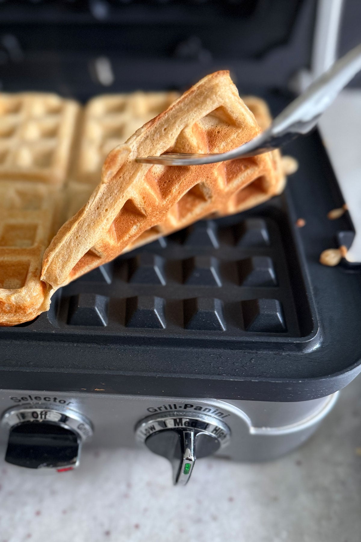Finished waffle being taken out of waffle iron. 
