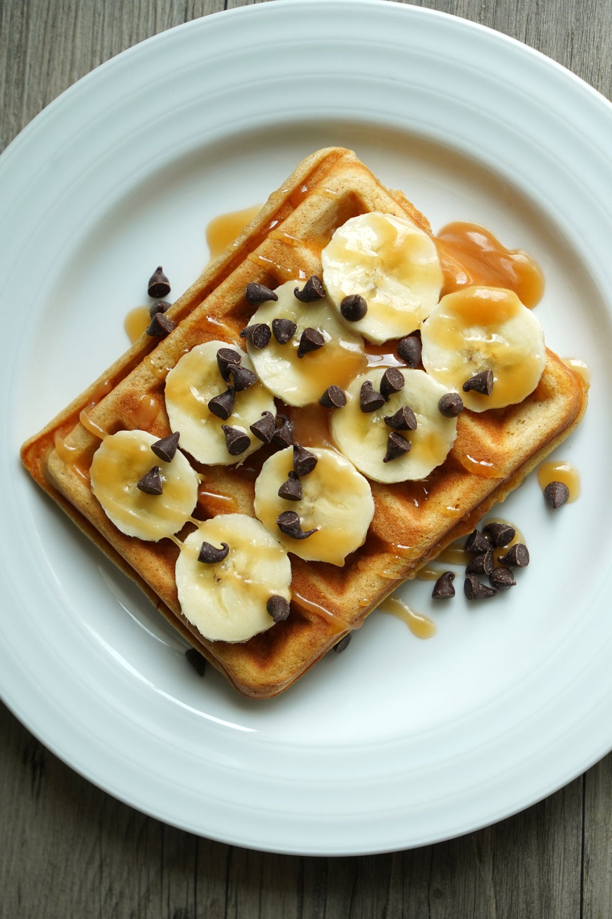 Waffle served with banana slices, chocolate chips and salted caramel sauce.