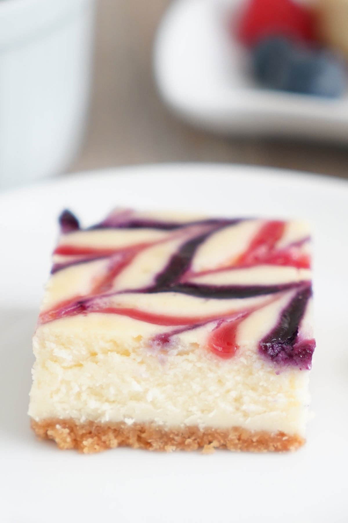Close up of single cheesecake bar to show midsection of crust and cheesecake texture.