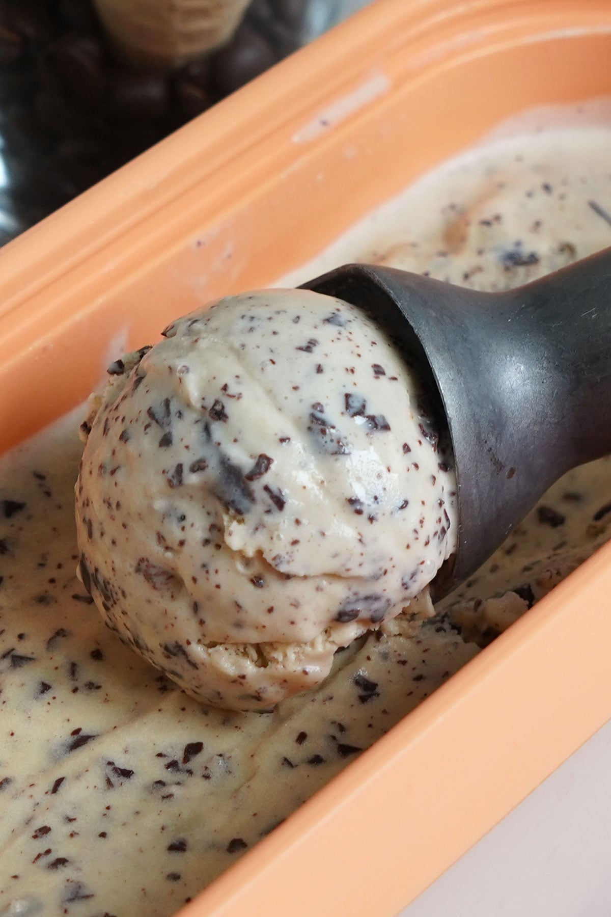 Espresso ice cream being scooped out of container.