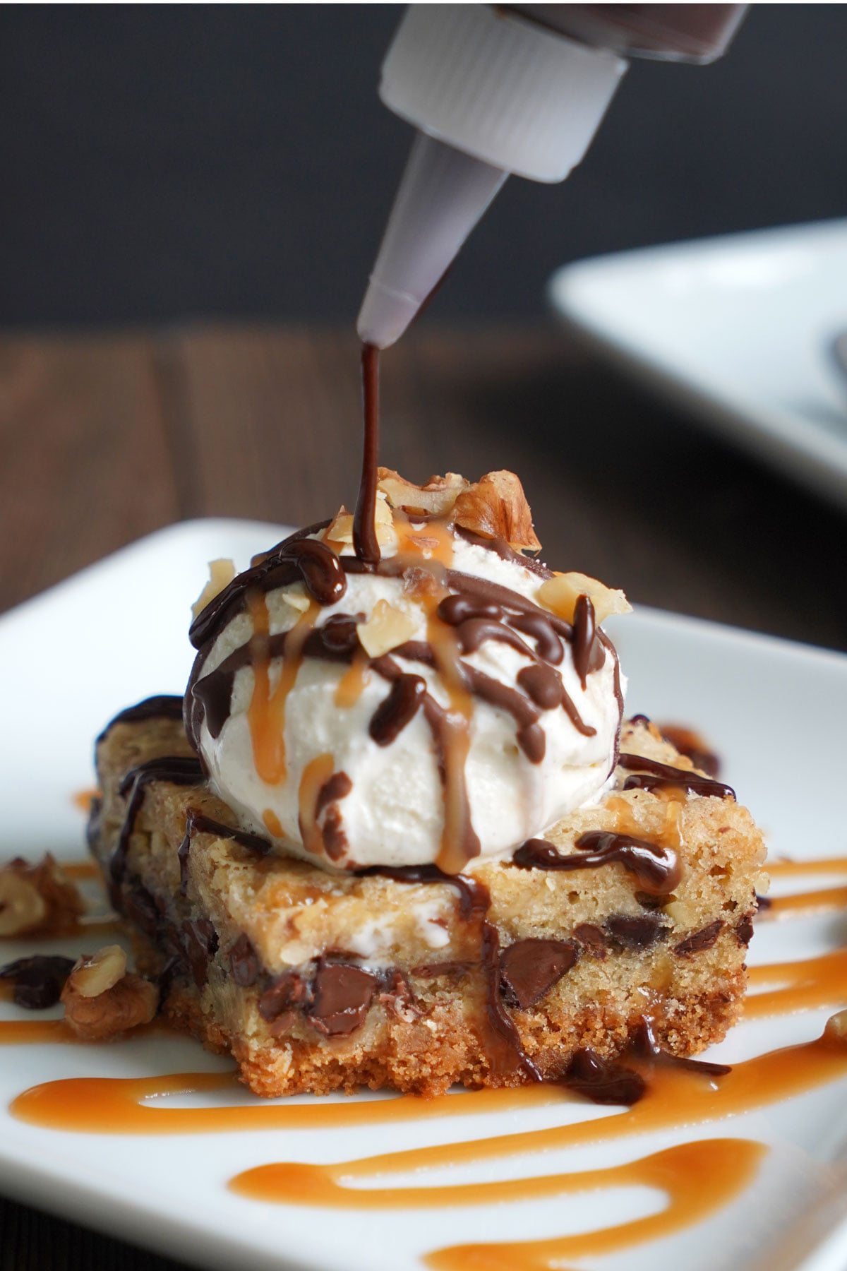 Chocolate sauce being drizzled over the vanilla ice cream topped chocolate chip paradise pie.