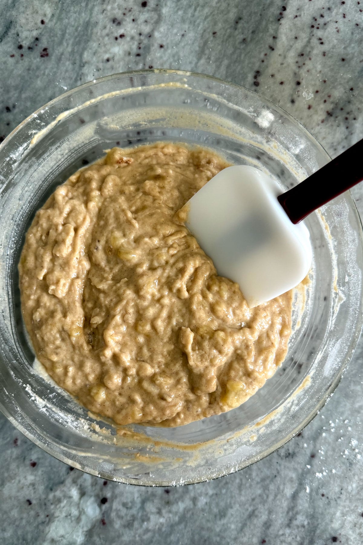 Banana bread batter made with pancake mix in a glass bowl with spatula.