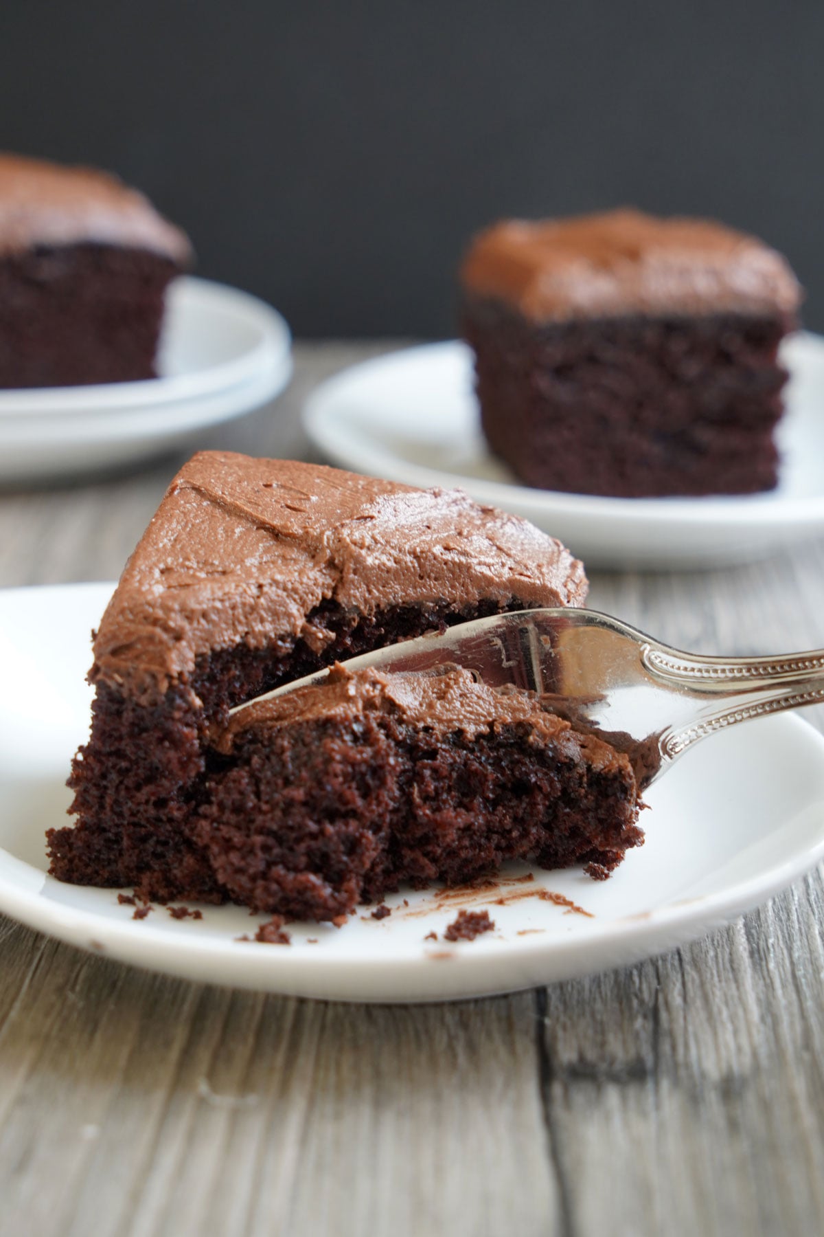 Square of fudge-frosted chocolate cake with a fork taking out a bite.
